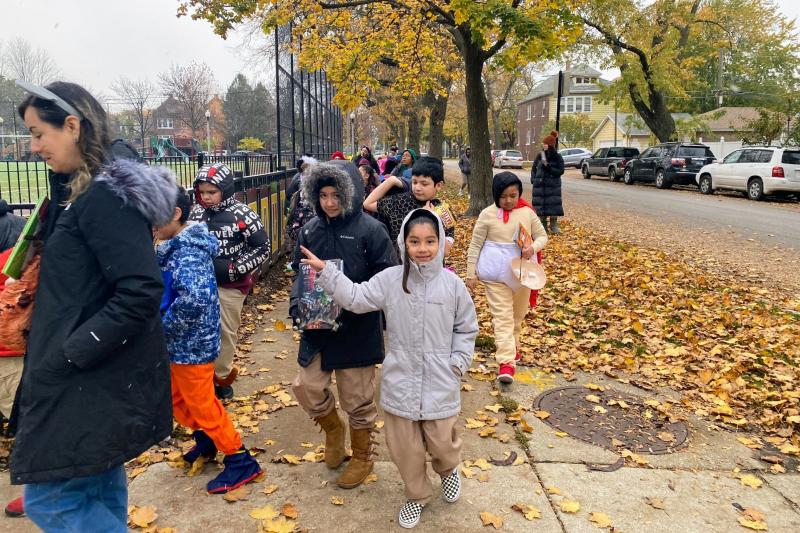 a group of children walking on a sidewalk