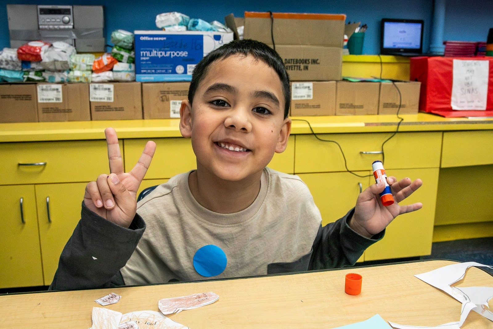 smiling student holding glue stick