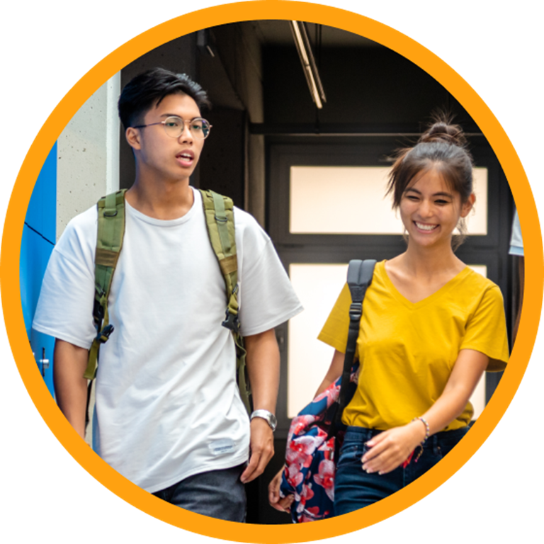 Two students talking while walking down a hallway