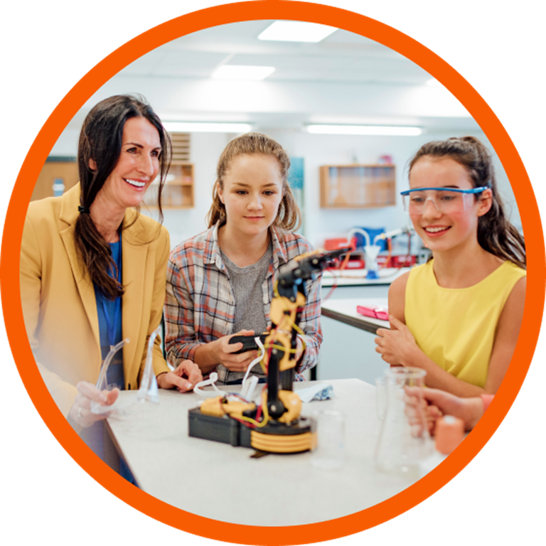 Teacher showing two students how to use a robotic arm