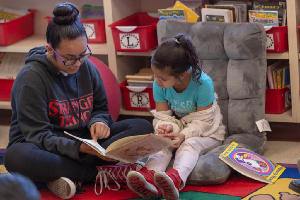 Older student reading to younger student