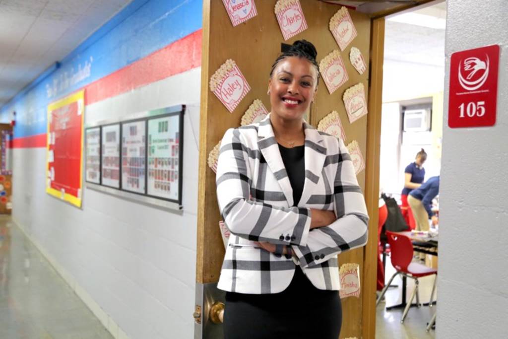 Teacher stands in front of a classroom door