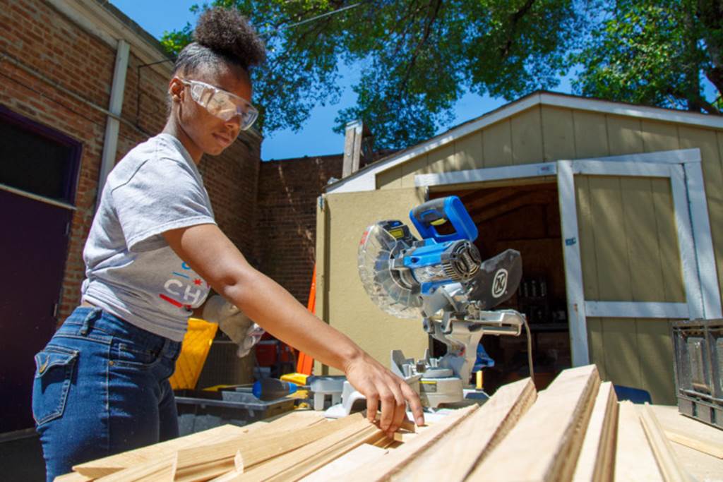 Teen cutting wood with a saw