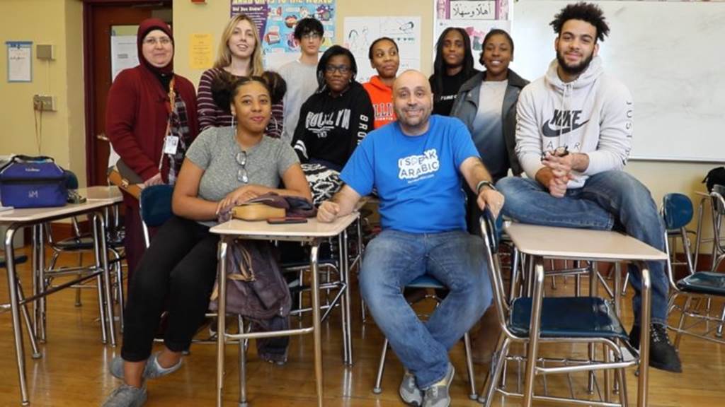 Students sit behind teachers