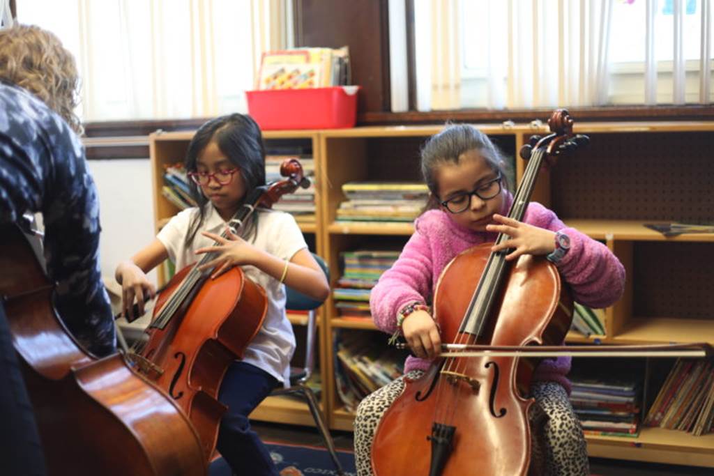 Two girls playing the cello