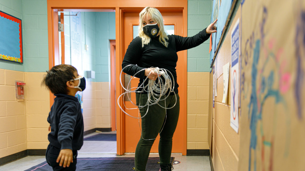 A teacher pointing to something on the wall