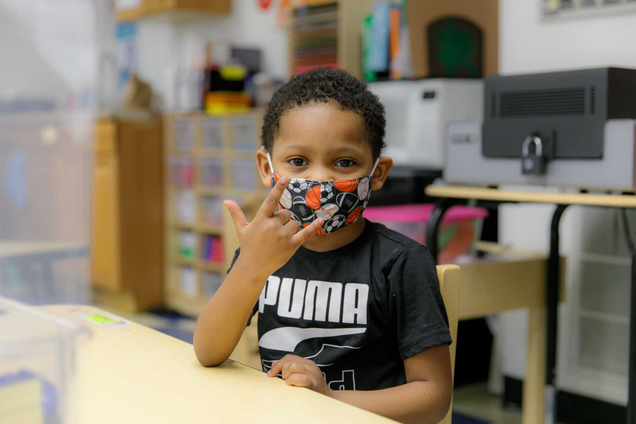 A boy holding up a rock symbol