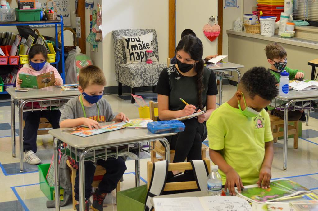 A teacher monitoring a student's reading