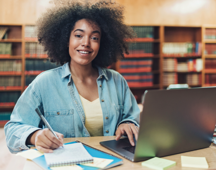 Student working within a library to finish a virtual assignment